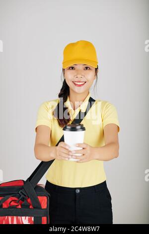 Ritratto di sorridente giovane ragazza asiatica corriere che dà tazza di caffè take away Foto Stock