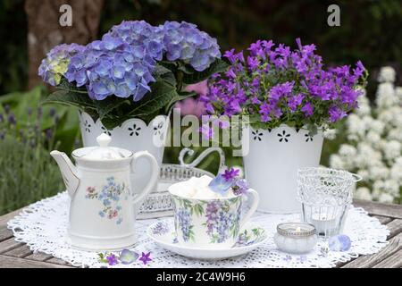 decorazione da tavolo con porcellana con ornamento floreale e fiori viola Foto Stock