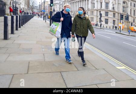 Londra, Inghilterra, Regno Unito. Due giovani che indossano maschere a Whitehall, Westminster, all'inizio della crisi del virus Corona, marzo 2020 Foto Stock