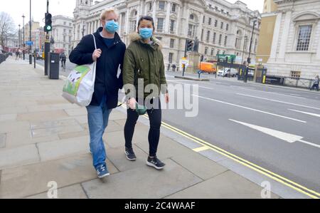 Londra, Inghilterra, Regno Unito. Due giovani che indossano maschere a Whitehall, Westminster, all'inizio della crisi del virus Corona, marzo 2020 Foto Stock