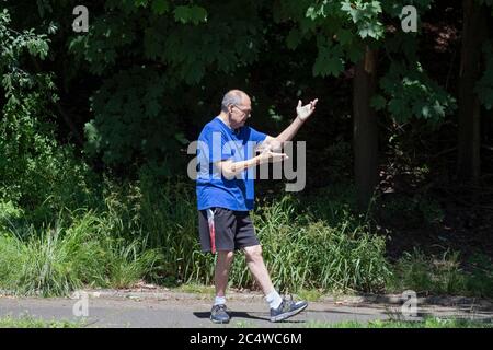 Un uomo anziano fa esercizi di Tai Chi nel Parco di Kissena a Flushing, Queens, New York City. Foto Stock