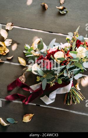 bouquet nuziale di rose bianche e rosse, peonie, rami di eucalipto, alstroemeria e crisantemo, bacche rosse con nastri bianchi e maroon Foto Stock