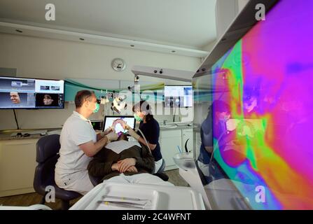 Dresda, Germania. 24 Giugno 2020. ILLUSTRAZIONE - il dentista Conrad Kühnöl (l) e un igienista dentale esaminano un paziente con un microscopio fluorescente nella pratica dentale. (Posed scene) Credit: Roberto Michael/dpa-Zentralbild/ZB/dpa/Alamy Live News Foto Stock