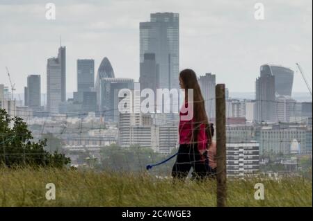 Londra, Regno Unito. 28 Giugno 2020. Vista della città di Londra mentre si affaccia in lontananza sul verde. La gente gode dei vari spazi di Hampstead Heath che si schivano tra forti docce a pioggia e intervalli di sole. Il "blocco" continua ad essere attenuato per l'epidemia di Coronavirus (Covid 19) a Londra. Credit: Guy Bell/Alamy Live News Foto Stock