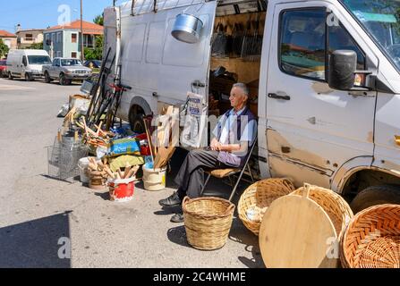 Uomo che vende i cesti e gli ironmongers merci al mercato domenicale nella piccola città di Kopanaki, Messinia nord-occidentale, Peloponneso, Grecia. Foto Stock