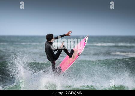 Azione spettacolare come un surfista prende in aria da un'onda a Fistral a Newquay in Cornovaglia. Foto Stock