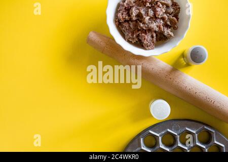 Preparazione per cucinare gnocchi di carne su un tavolo da cucina giallo, sfondo con copyspace. Foto Stock