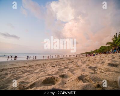 Kuta, Bali, Indonesia - 15 gennaio 2019: I turisti al tramonto si siedono su una popolare spiaggia turistica di Bali. Foto Stock