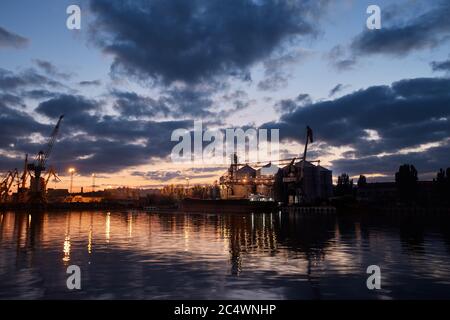 Big Grain terminal al porto. Trasporto alla rinfusa di cereali dal trasporto su strada alla nave durante la notte. Caricamento di prodotti di grano sulla nave da grandi elevatori a. Foto Stock