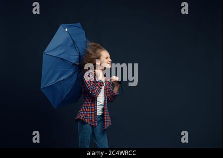 La bambina tiene un ombrello, effetto vento Foto Stock