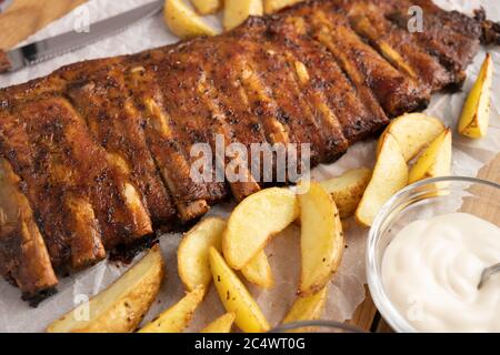 Costolette di maiale cotte con patatine fritte con salsa al barbecue e aglio e birra Foto Stock