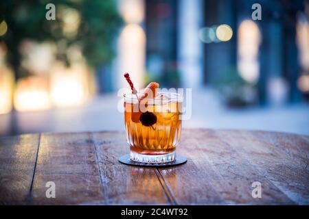 si può vedere un rum vecchio stile su un cocktail di ghiaccio su un tavolo di legno il cui colore è arancione trasparente con uno sfondo sfocato Foto Stock