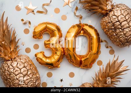 biglietto per la celebrazione del 30° compleanno con palloncini d'oro e ananas dorati Foto Stock