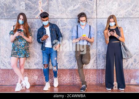 gruppo di amici multirazziali con maschere facciali che utilizzano gli smartphone per condividere contenuti sui social network Foto Stock