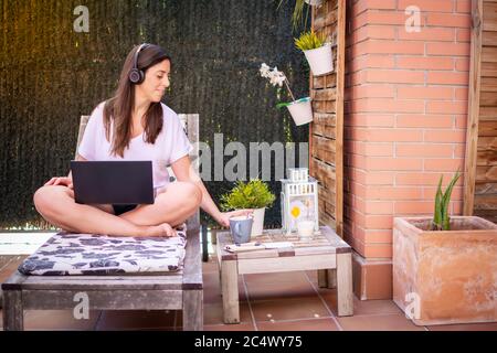 Donna freelance, il blogger di viaggio lavora su un computer portatile. Seduta su un lettino in giardino Foto Stock