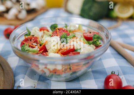 Insalata vegana fresca all'aperto su tovagliolo scacchi blu. Concetto di cibo vegano all'aperto Foto Stock