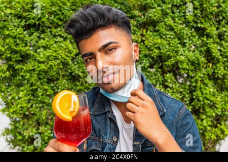 Ritratto maschile di giovane adulto che beve cocktail colorato al bar esterno con maschere facciali - nuovo concetto di stile di vita normale con gente felice tostatura drink Foto Stock