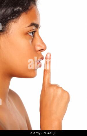 Primo piano di una giovane e bella di carnagione scura la donna con il dito sulle labbra su uno sfondo bianco. Concetto di silenzio Foto Stock