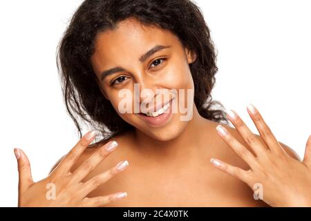 Giovane donna scura con pelle che mostra la sua manicure su sfondo bianco Foto Stock