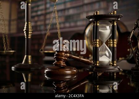 Tema della legge. Biblioteca di corte. Gavel, scala e statua di Themis su tavolo bruno splendente. Raccolta di libri legali nella libreria. Foto Stock