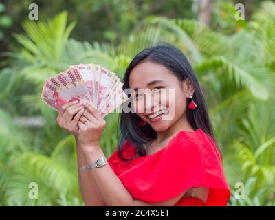 Denaro indonesiano nelle mani di una ragazza asiatica. Foto Stock