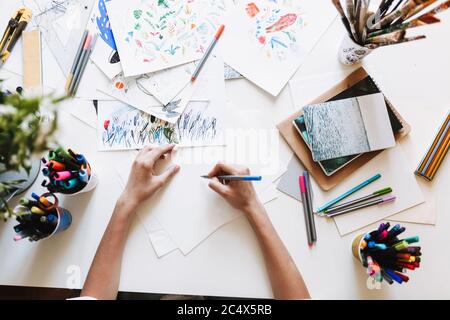 Chiudi la ragazza alla scrivania utilizzando colorati pennarelli per disegnare a casa isolato Foto Stock