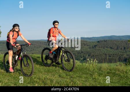 Nonna con mountain bike elettrica e granddaughter senza aiuto elettrico su un sentiero liscio prato nella zona della Svizzera Franconia di Bavari Foto Stock