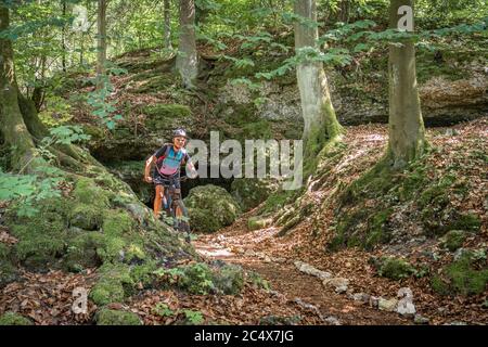 Donna anziana in fase di svolgimento sulla sua mountain bike elettrica su un sentiero roccioso nella Svizzera Franconia, Baviera, Germania Foto Stock