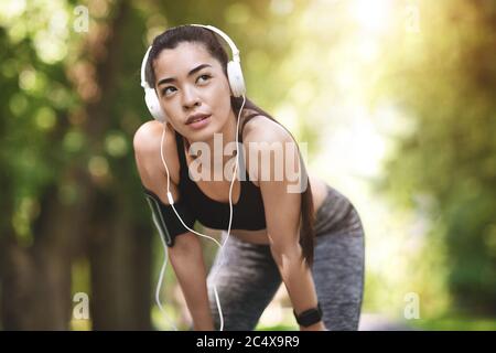 Stile di vita sportivo. Ragazza asiatica motivata che si riposa durante il jogging nel City Park Foto Stock