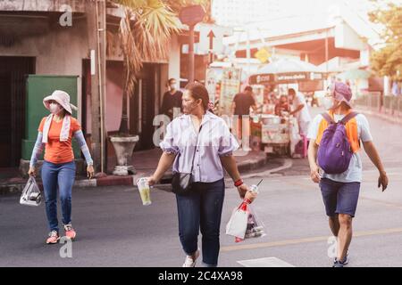 Persone con maschera di protezione che porta borsa di plastica nella sua mano che attraversa la strada. Foto Stock