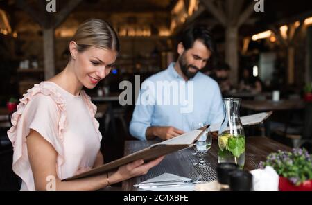 Una coppia felice, seduta all'interno del ristorante, guardando il menu. Foto Stock