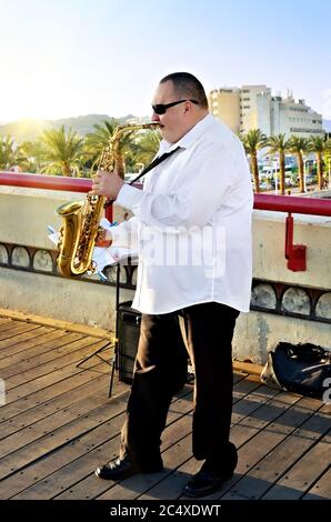 EILAT, ISRAELE - 31 MARZO 2015: Musicista non identificato suona in strada a Eilat al tramonto. Questo è uno dei più popolari per gli spettacoli all'aperto Foto Stock