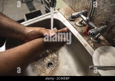 Primo piano di un operaio di fabbrica maschile che lavano le mani nel lavello Foto Stock