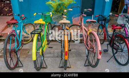 Una fila di biciclette d'epoca dipinte in colori vivaci, parcheggiate su una strada a Pondicherry, India. Foto Stock