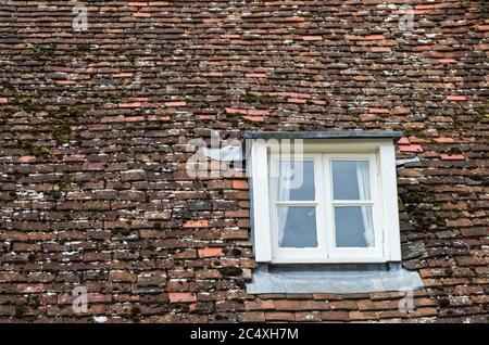 Vecchio tetto tegole con piccola finestra sul tetto su un edificio a Dorchester sul Tamigi, Oxfordshire, Regno Unito Foto Stock