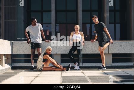 gruppo fitness che si rilassa insieme dopo l'allenamento. Gruppo multietnico di corridori che riposano dopo una sessione di allenamento in città. Foto Stock