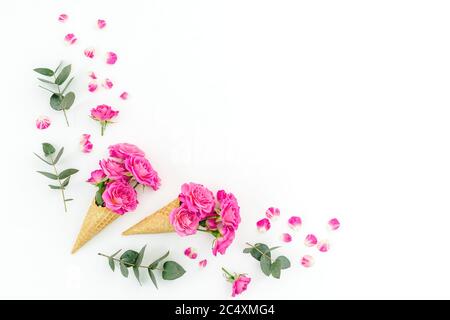 Concetto floreale con rose rosa ed eucalipto su sfondo bianco. Disposizione piatta, vista dall'alto. Foto Stock