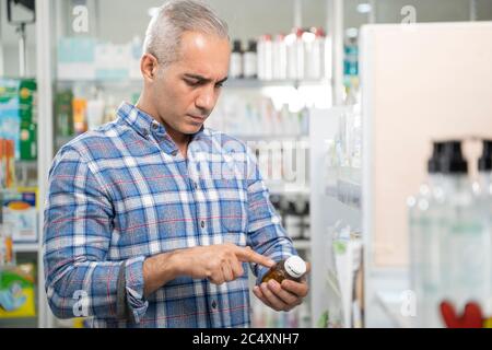 Uomo lettura etichetta del flacone di medicina. Foto Stock