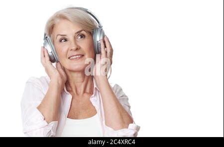 Una donna matura allegra ascolta la musica in cuffia. Ritratto di felice bella signora anziana. Isolato su bianco Foto Stock