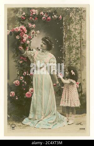 Cartolina di auguri sentimentali francesi antichi dei primi del 1900 - madre e figlia carina tenendo la sua mano picking rose, Francia, circa 1912 Foto Stock
