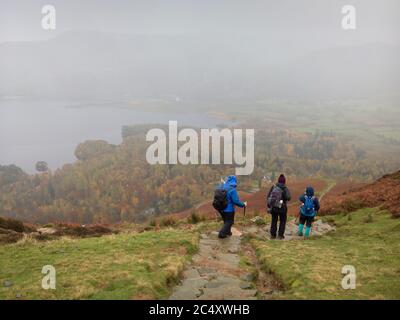 I camminatori caddero che discendono Cat Bells in Borrowdale con Derwent Water Beyond nel Lake District National Park, Cumbria, Inghilterra. Foto Stock