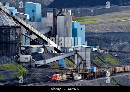 Un Canadian National Railway treno merci il caricamento del carbone a carbone impianto di trasformazione delle colline ai piedi delle montagne rocciose di Alberta in Canada Foto Stock