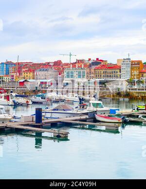 Nuvoloso citycsape con yacht e barche a motore ormeggiate dai piloni in marina, Gijon, Asturias, Spagna Foto Stock