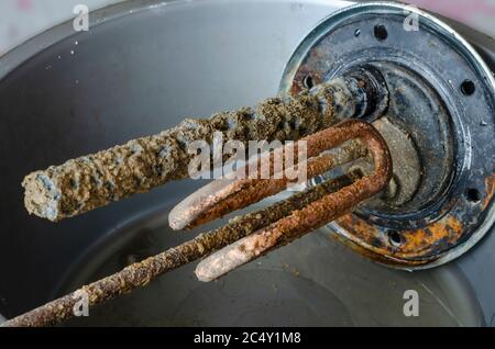 Flangia del riscaldatore dell'acqua con anodo, sensore di temperatura ed elemento riscaldante elettrico. Primo piano di un vecchio dettaglio di scaldabagno. Assistenza e riparazione. Selettivo Foto Stock