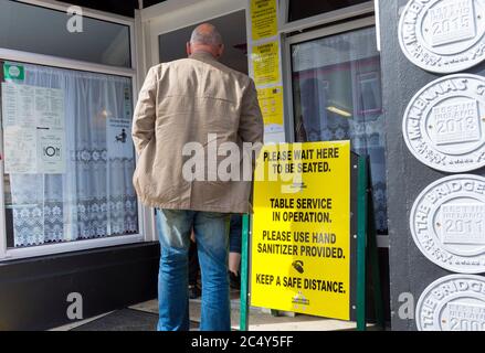 Ardara, Contea di Donegal, Irlanda 29 giugno 2020. Il premiato "Charlie's Cafe" apre per la prima volta da marzo a causa delle precauzioni pandemiche di Covid-19. I clienti devono attendere di essere seduti e utilizzare l'igienizzatore a mano come osservante "distanza sociale" nel bar. Foto Stock