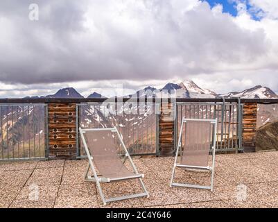 Vista panoramica sulle montagne dalla terrazza panoramica con sedie a sdraio; Monte ghiacciaio Weisskugel (palla bianca) nelle alpi Ötztal, Schnalstal, Südtirol Foto Stock