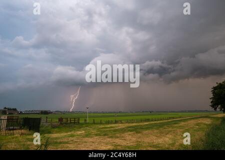 Tempesta di temporali grave che si avvicina su un campo. Il fulmine colpisce la terra. Foto Stock