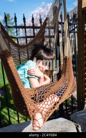 Ragazzo che dormiva in un'amaca in un cortile in una giornata di sole. Foto Stock