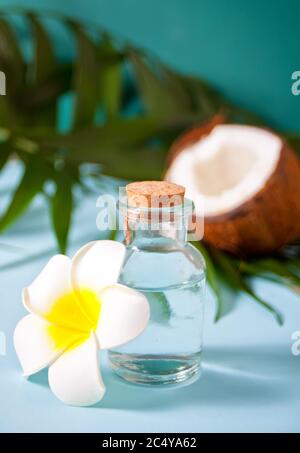 olio di noce di cocco naturale con cocco e fiori nelle vicinanze Foto Stock