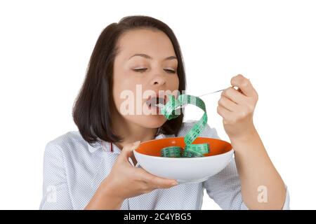 Perdita di peso e concetto di stile di vita sano. Fitness Donna cercando di mangiare nastro di misurazione su uno sfondo bianco Foto Stock